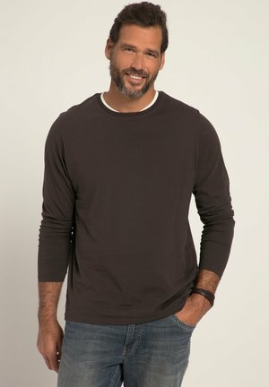 Dunkelbraun longsleeve Hemd mit einem weißen Rundhalsausschnitt, kombiniert mit hellblauen Jeans; glatte Stofftextur und entspannte Passform.