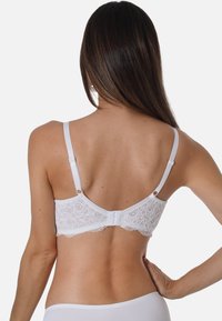 White lace bra with a floral pattern, adjustable straps, and a hook-and-eye closure at the back. Smooth fabric and delicate trim.