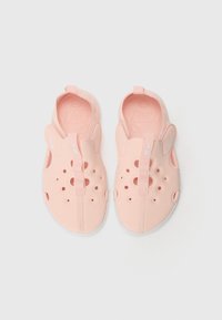 Világos rózsaszín slip-on cipők perforált dizájnnal, textúrázott talpbetéttel, fehér talppal és logós húzófüllel.