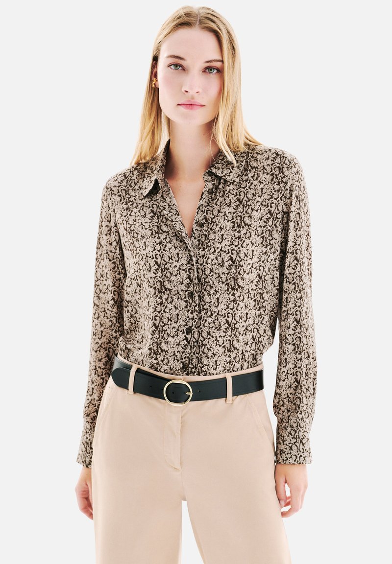 Chemise à manches longues en tissu marron et beige avec un motif détaillé, dotée d'un col et d'une fermeture à boutons, assortie à une ceinture noire.