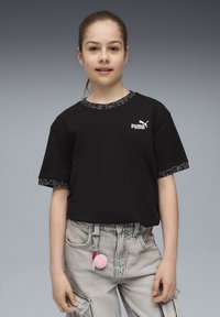 Must have lühikeste varrukatega must T-särk, millel on leopardimustriga äär ja valge Puma logo. Kombineeritud heledate hallide cargo-pükstega, millel on roosa pom-pom aksessuaar.