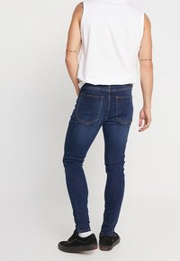 Smal passform mörkblå jeans i denim, med fem fickor, diskret sömnad på bakfickorna och medelhög midja.