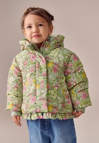 Šilta žalia striukė su rožiniais, geltonais ir baltais gėlių raštais, su kapišonu, spaudėmis ir raukšlėtu apvadu. Dėvima kartu su džinsais.