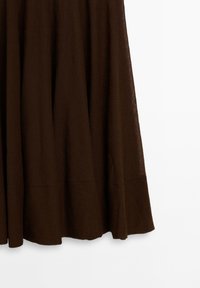 Brązowa lniana spódnica o zwiewnym kroju z rozkloszowanym dołem. Materiał ma subtelną teksturę, nadając lekki i przewiewny wygląd.