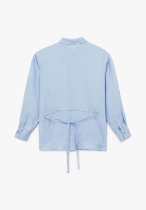 Chemise à manches longues bleu clair avec un col, un détail de nœud au dos et des poignets à boutons. Fabriquée en tissu doux et légèrement texturé.