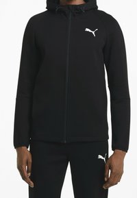 Sudadera deportiva negra con cremallera frontal, capucha y logo Puma blanco de marca en el frente; presenta tejido suave y diseño ajustado.