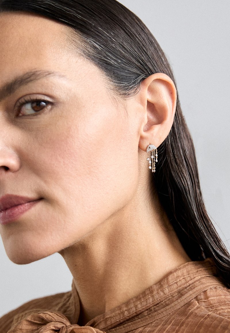 Silver earrings with cascading chains, featuring small sparkling stones. Round top design highlights delicate details and texture.