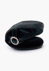 Pantofole verdi in velluto con forma arrotondata, suola in gomma e anello decorativo in strass. Texture morbida con una leggera lucentezza.