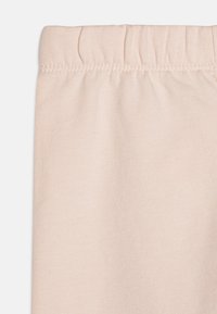 Lyserøde leggings med elastisk linning, glat tekstur og lige snit. Stoffet ser strækbart og blødt ud, velegnet til afslappet brug.
