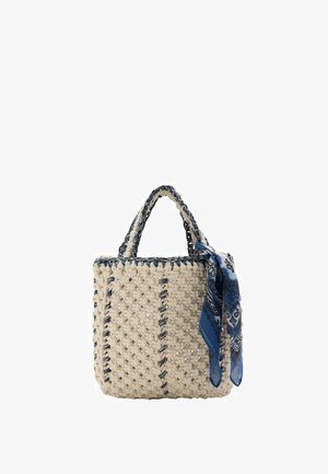 Sac à main carré en crochet crème avec bordures et poignées bleu foncé, décoré d'un foulard noué à motif cachemire bleu sur la poignée.