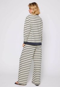 Conjunto de ropa de casa a rayas en crema y azul marino, que presenta una parte superior de corte relajado con mangas largas y pantalones de pierna ancha, mostrando una tela de punto texturizada.