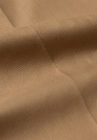 Brązowa tkanina o gładkiej fakturze, z delikatnymi prążkowanymi detalami i miękkim połyskiem, złożona w taki sposób, by uwidocznić jej głębokość i strukturę.