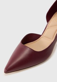Burgundy leather high-heeled shoe with a pointed toe and an open ankle design, featuring a smooth surface and a cushioned insole.