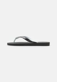 Svart gummiflip-flop sandal med en teksturert fotseng og en kontrastfarget sort og hvit stropp med merkevarelogo. Enkelt, flatt design.