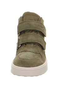 Zielony zamszowy but za kostkę z dwoma rzemykami na rzep, zaokrąglonym noskiem i białą gumową podeszwą. Wnętrze wyściełane miękką tkaniną dla komfortu.