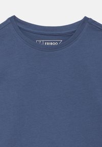 Μπλε μπλουζάκι με στρογγυλή λαιμόκοψη και ορατές ραφές, με μια μικρή τυπωμένη ετικέτα στο εσωτερικό του λαιμού που δείχνει μέγεθος 7/8 ετών.