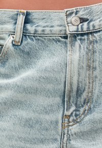 Ανοιχτό μπλε τζιν σορτσάκια με υφή, διαθέτουν κλείσιμο μπροστά με κουμπί, ορατές ραφές και εφέ ξεθωριασμένου πλυσίματος.