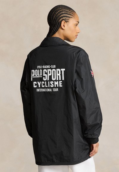 Schwarze, leichte Jacke mit Kragen, elastischen Bündchen und "POLO SPORT CYCLISME INTERNATIONAL TOUR" in Weiß auf der Rückseite gedruckt.