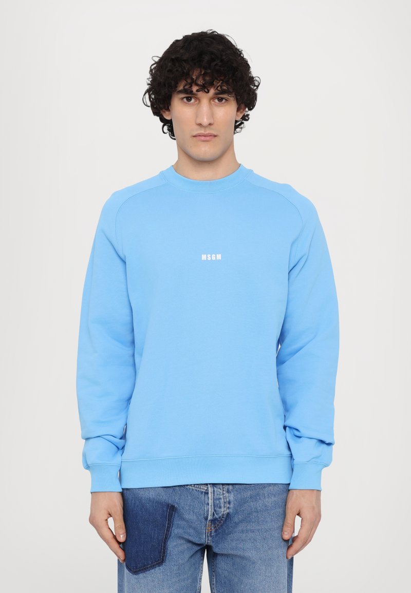 Sudadera azul claro con cuello redondo, mangas largas y un logo blanco de "MSGM" en el pecho. Fabricada con una tela suave y lisa.