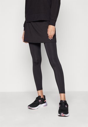 Fekete sportos ruha fekete leggings fölött, fekete sportcipővel, amelynek pink akcentusai és mintás talpa van. Egységes textúrák végig.