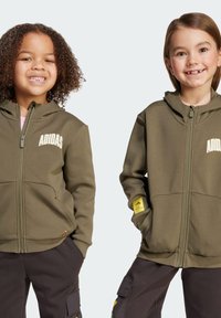 Olijf groene zip-up hoodies met frontzakken, "ADIDAS" logo in het wit en gele accenten op de mouwen. Zacht, gestructureerd stof geschikt voor kinderen.