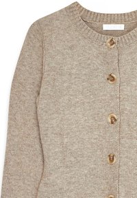 Bežs adīts kardigans ar apaļu apkakli, ribotām malām un sešām apaļām pogām priekšpusē. Mīksta tekstūra ar gludu apdari.