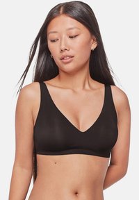 Bralette negra sin aros con un profundo escote en V y tirantes anchos, que presenta una tela suave y elástica, así como un diseño minimalista.