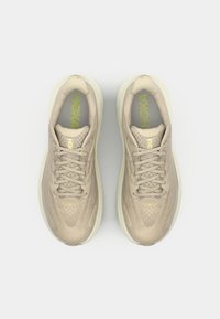Beige running shoes with a textured mesh upper, contrasting yellow accents, and sturdy laces. Features a padded collar and cushioned sole.