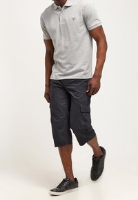 Grå pikétröja med korta ärmar, logotyp på bröstet; marinblå cargoshorts med sidofickor; svarta sneakers med snörning.