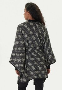 Wrap nero con motivo geometrico più chiaro, maniche larghe e vestibilità ampia, realizzato in tessuto testurizzato.