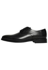 Chaussure habillée noire en cuir avec lacets, dotée d'une finition lisse et de détails perforés sur les côtés, elle possède un bout arrondi et un talon bas.
