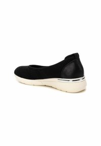 Zapato negro tipo slip-on con una parte superior de punto transpirable, un brillante acento en el tacón negro y una suela de goma blanca con detalles plateados.