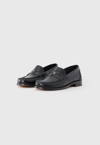 Black leather loafers with a stitched design, flat heel, and a small gold accent on the front. Smooth texture and classic shape.