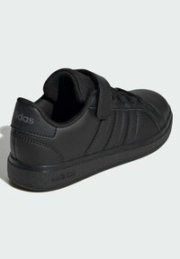 Czarny sneaker Adidas z gładką skórzaną cholewką, teksturowanym językiem z tkaniny, sznurowadłami i zapięciem na rzep oraz gumową podeszwą.