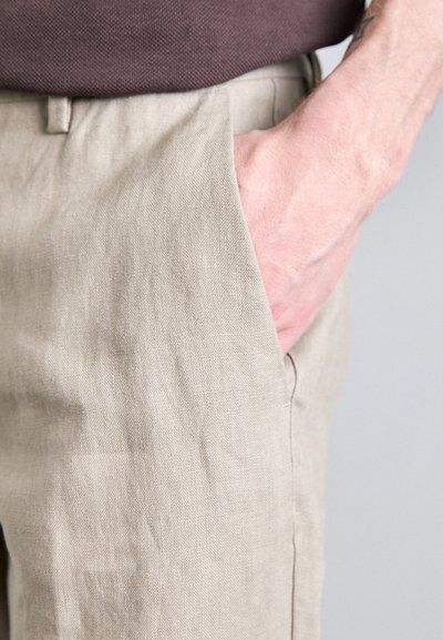 Pantalons en lin beige à coupe slim, dotés de poches latérales et d'une texture subtile. Ceinture à boutons avec passants pour ceinture.