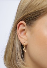 Gyldent halvmåneørering med pink ædelstene, der har et struktureret design. Hænget fra en lille hoop-beslag.