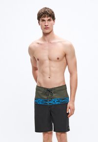 Μπόρντσορτς με πράσινη ζώνη μέσης και μπλε γεωμετρικά σχέδια, που μεταβαίνουν σε μαύρο ύφασμα. Διαθέτουν κορδόνι για ρύθμιση.