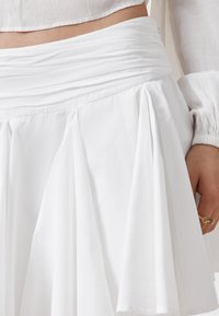 Witte rok met geplooid ontwerp en gathered tailleband. Gemaakt van lichtgewicht stof, met een zachte textuur en een gladde afwerking.