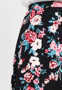 Jupe fleurie noire arborant un motif vibrant de fleurs roses et turquoise, avec un tissu doux et une taille cintrée.