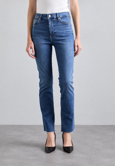 High-waisted denim jeans in medium blue. Features a fitted silhouette with five pockets, button closure, and raw hems. Smooth texture.