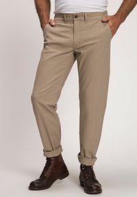 Kahvi chinos dengan potongan lurus, dilengkapi dengan penutupan kancing, saku samping, dan lengan yang digulung, dipadukan dengan sepatu bot coklat dengan tali.
