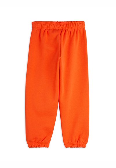 Oransje joggebukser laget av myk resirkulert polyester, med elastisk midje og elastiske mansjetter ved anklene. Enkel design, uten lommer.