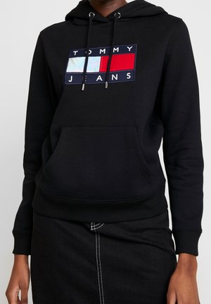 Felpa nera con cappuccio, caratterizzata da una tasca a marsupio frontale, un cappuccio con cordino e un logo rettangolare a blocchi di colore con accenti rossi, blu e bianchi.