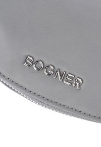 Borsa in tessuto grigia caratterizzata da una texture liscia e un logo "BOGNER" argentato. I bordi sono cuciti con dettagli raffinati.