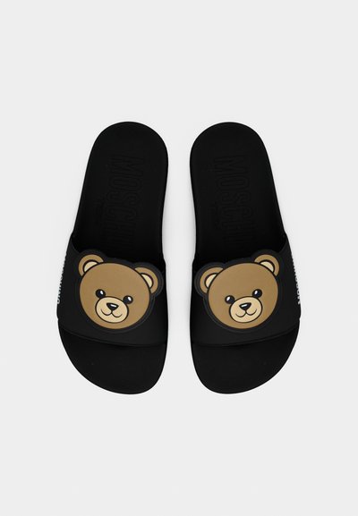 Sandales à glissière noires avec des visages de teddy bear marron souriants sur les brides et "MOSCHINO TEEN" embossé sur les semelles intérieures.