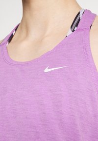 Top sportivo viola con scollatura rotonda e spalline sottili. Presenta un piccolo logo bianco sul davanti e una texture morbida e leggera.
