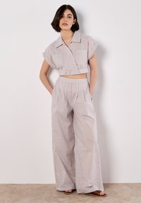 Camisa cropped a rayas y pantalones de pierna ancha en tela ligera, con rayas horizontales azules y beige, con un corte relajado y grandes bolsillos.