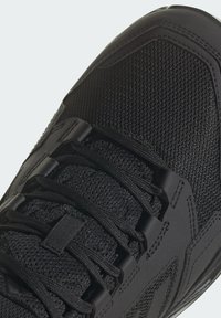 Czarna sportowa buty z teksturowaną siateczką, mocnymi sznurowadłami i gumowymi akcentami. Okrągły kształt noska z wyściełaną podeszwą.