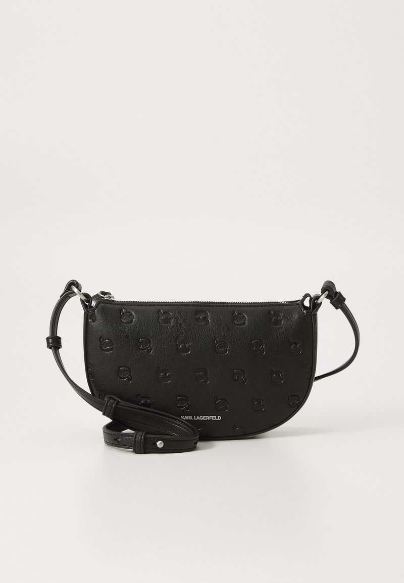 Sac à bandoulière en cuir noir avec motif de logo embossé, forme courbée, fermeture à glissière et bandoulière réglable. Accents en métal argenté.