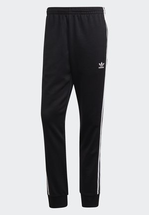 Pantaloni sportivi neri in tessuto morbido, con strisce bianche sui lati e una vita elasticizzata. Con orli a costeinato alle caviglie e un dettaglio con logo.